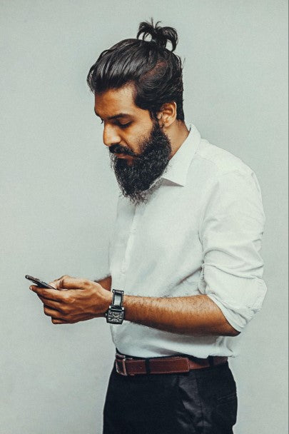 Man with bun and beard looking at phone